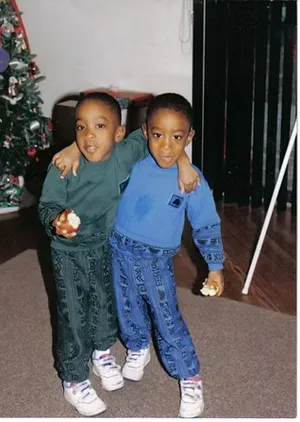 Young Lorenzo Santos with his brother in front of a Christmas tree